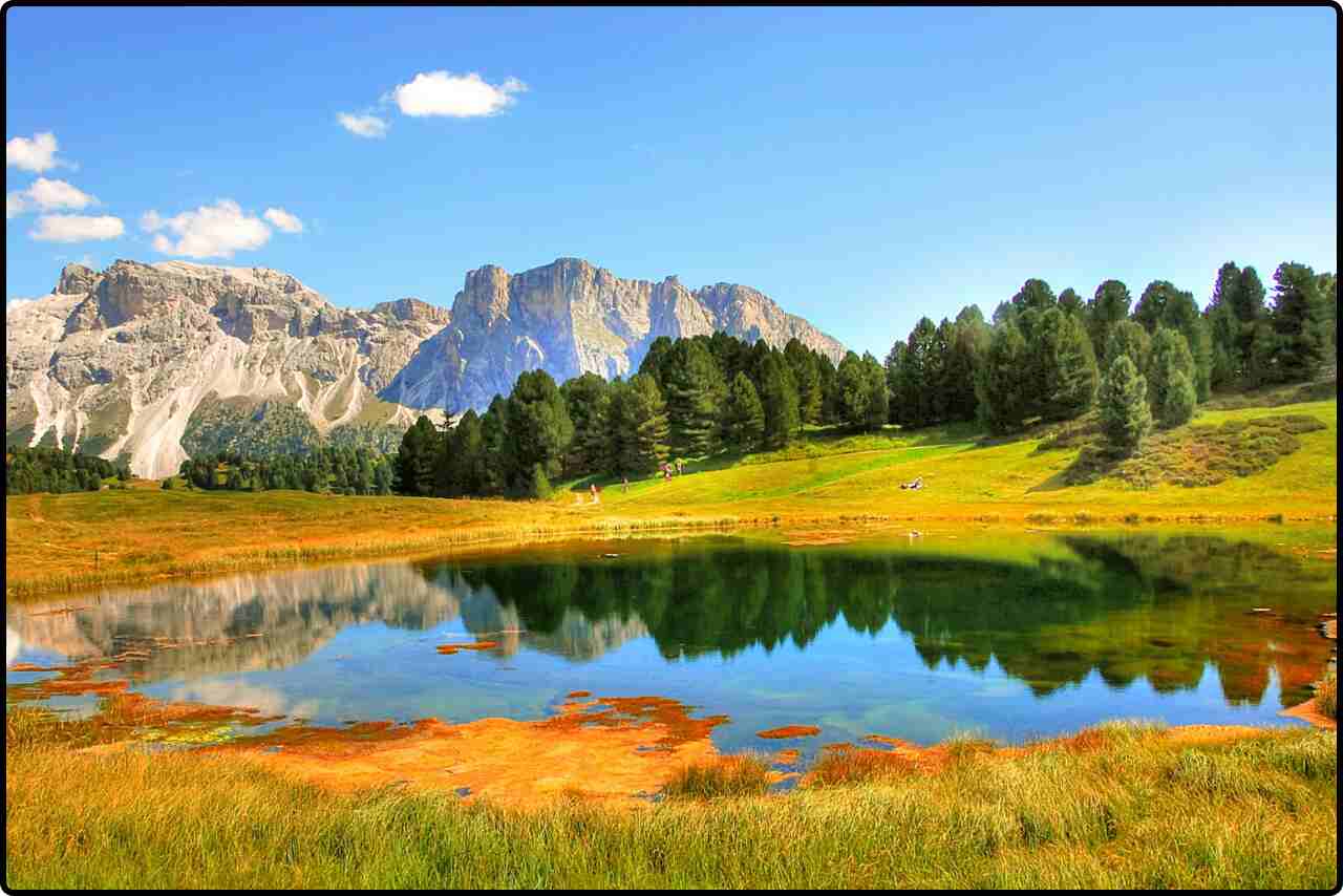 Scenic autumn landscape with vibrant red, orange, and yellow foliage reflecting in a calm lake